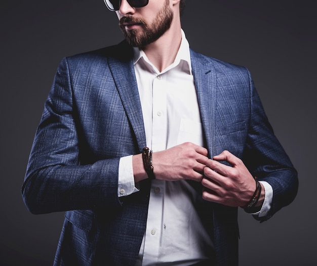 portrait of handsome fashion stylish hipster businessman model dressed in elegant blue suit on gray