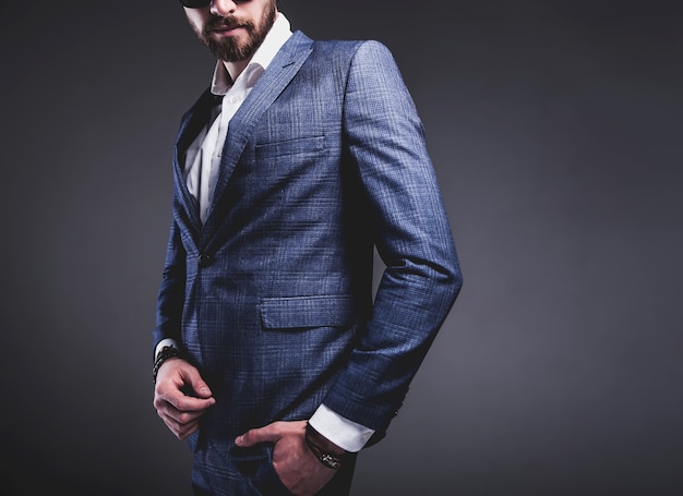 portrait of handsome fashion stylish hipster businessman model dressed in elegant blue suit on gray