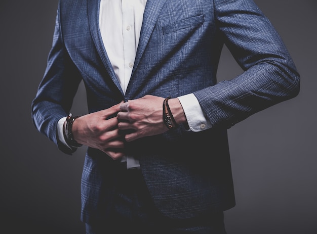 portrait of handsome fashion stylish hipster businessman model dressed in elegant blue suit posing on gray