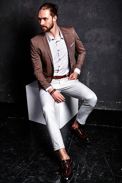 Портрет красивый модный стильный битник бизнесмен модель, одетый в элегантный коричневый костюм, сидя возле
