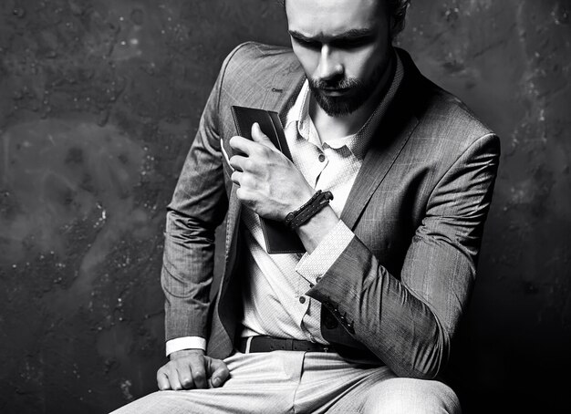 Портрет красивый модный стильный битник бизнесмен модель, одетый в элегантный коричневый костюм, сидя возле