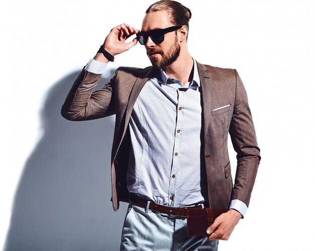 portrait of handsome fashion stylish hipster businessman model dressed in elegant brown suit in sunglasses