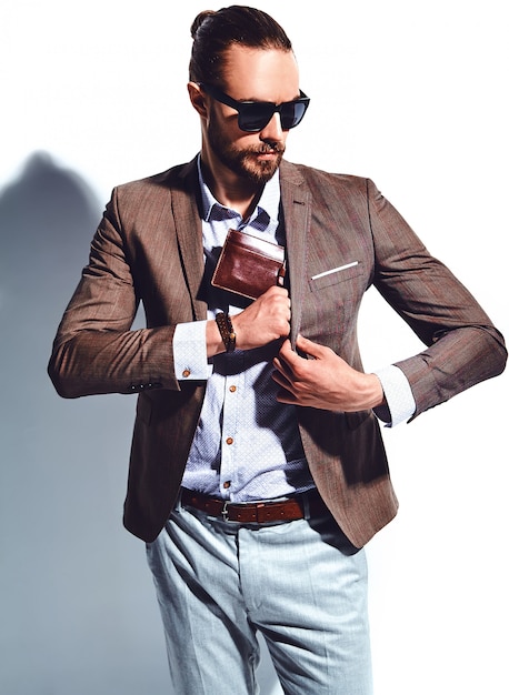 Free photo portrait of handsome fashion stylish hipster businessman model dressed in elegant brown suit in sunglasses