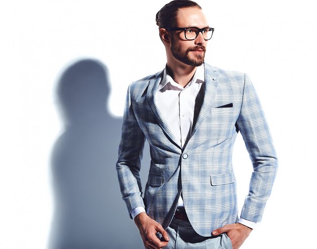 portrait of handsome fashion stylish hipster businessman model dressed in elegant light blue suit in glasses on white