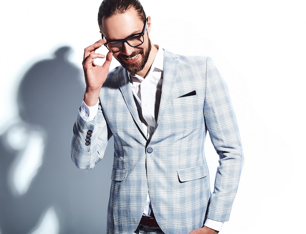 portrait of handsome fashion stylish hipster businessman model dressed in elegant light blue suit in glasses on white