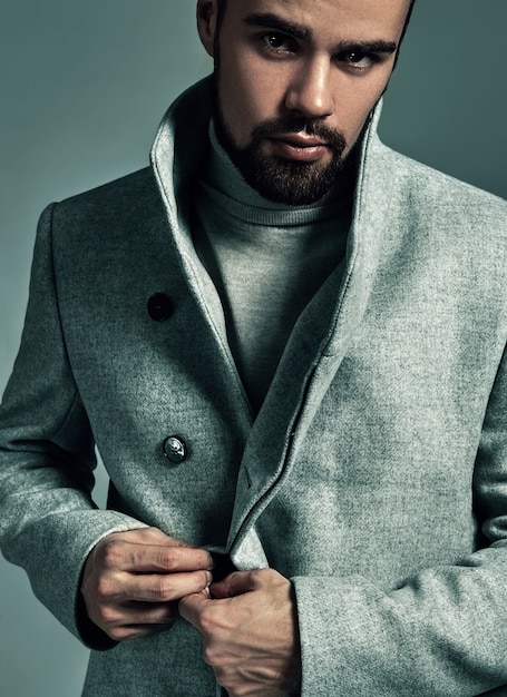 Free photo portrait of handsome fashion stylish hipster model dressed in warm overcoat  posing in studio.