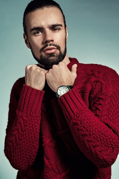 portrait of handsome fashion stylish hipster model dressed in warm red sweater  posing in studio.