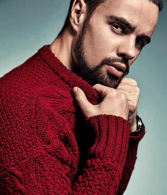 Портрет красивый модный стильный битник модели, одетые в теплый красный свитер, позирует в студии.
