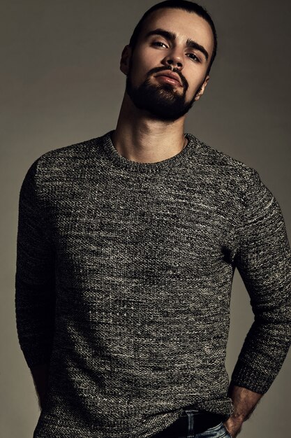 portrait of handsome fashion stylish hipster model dressed in warm sweater  posing in studio.
