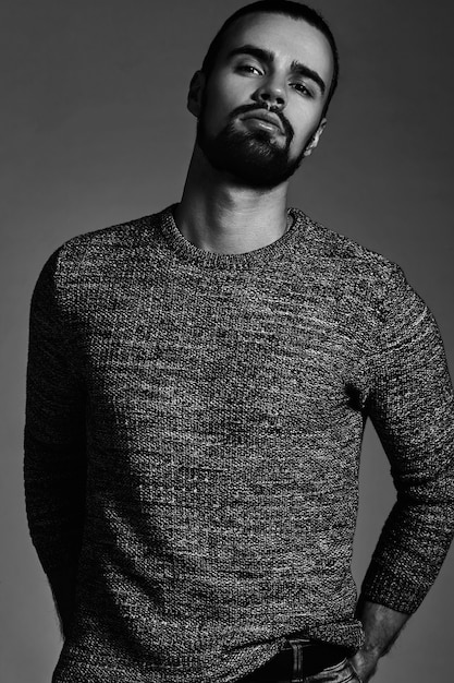 portrait of handsome fashion stylish hipster model dressed in warm sweater  posing in studio.