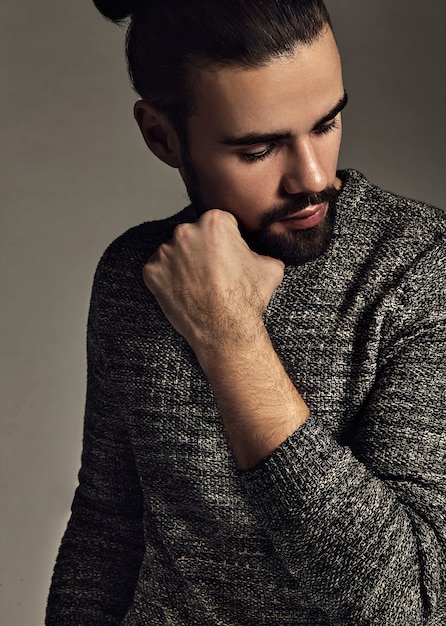 portrait of handsome fashion stylish hipster model dressed in warm sweater  posing in studio.