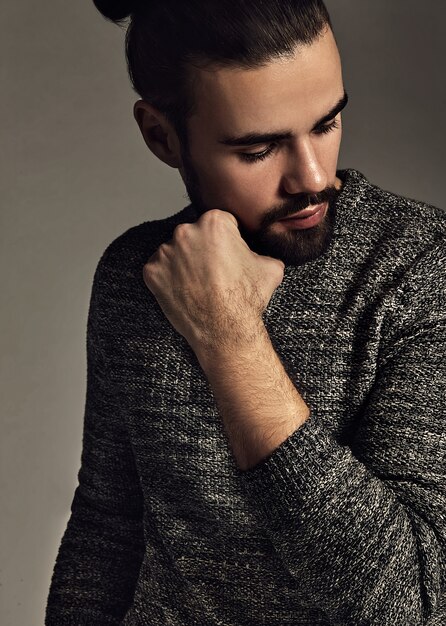 portrait of handsome fashion stylish hipster model dressed in warm sweater  posing in studio.