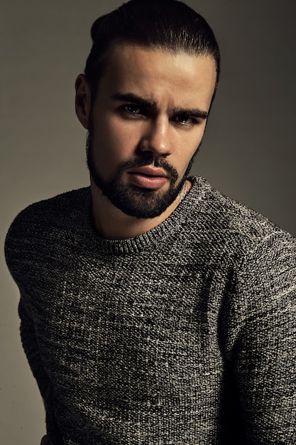 portrait of handsome fashion stylish hipster model dressed in warm sweater  posing in studio.