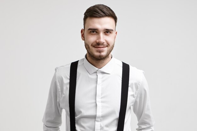 Portrait of handsome friendly looking young corporate worker with stylish haircut and beard looking at camera with happy confident smile, having good mood after he got promoted. Job and employment