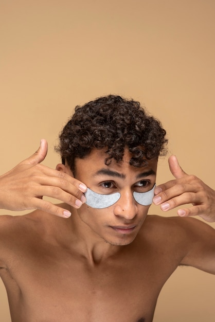 Free photo portrait of a handsome man applying under eye patches