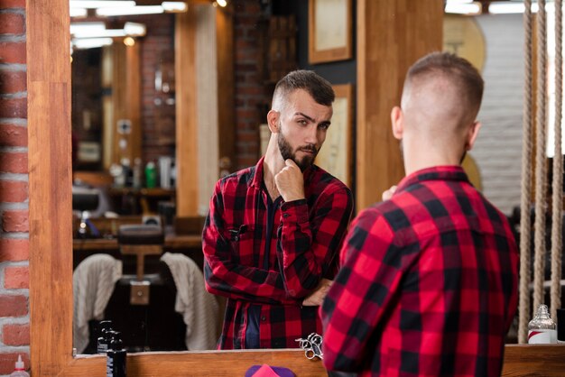 Портрет красивый мужчина, проверка его стрижка в зеркале