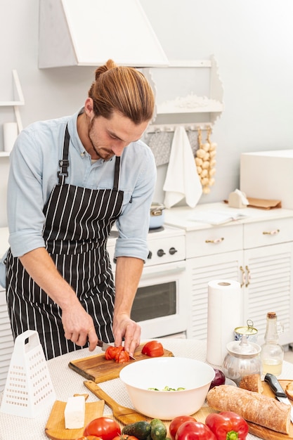 Portrait of handsome man cutting tomato