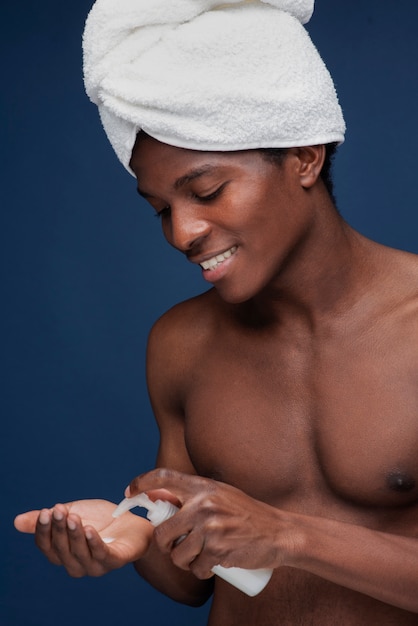 Foto gratuita ritratto di un bell'uomo che tira fuori la crema per il viso dalla bottiglia