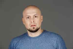 Free photo portrait of handsome man in grey shirt over dark wall