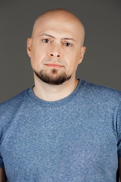 Portrait of handsome man in grey shirt over dark wall