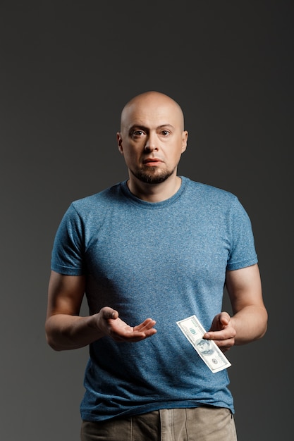 Free photo portrait of handsome man in grey shirt holding money over dark wall