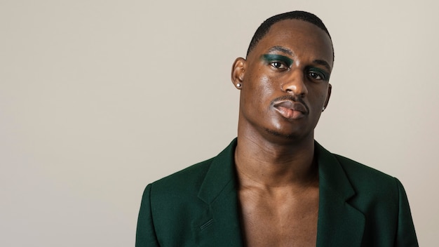 Portrait of handsome man posing in blazer and wearing make-up with copy space