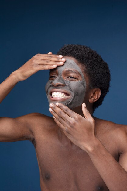 Portrait of a handsome man smiling with charcoal mask on his face