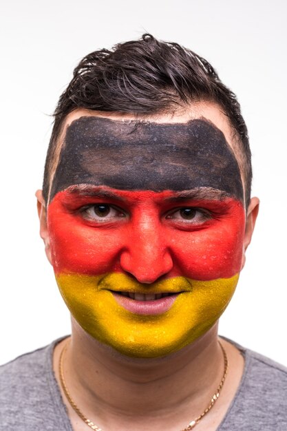 白で隔離の塗られた旗の顔を持つドイツ代表のハンサムな男の支持者の忠実なファンの肖像画。ファンの感情。