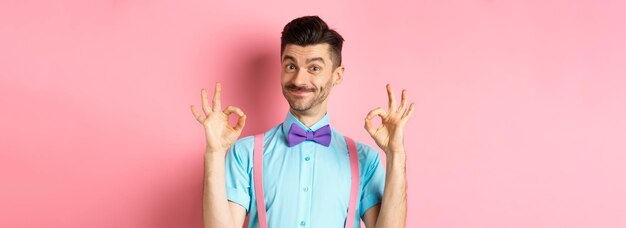 Free photo portrait of handsome man with moustache and bowtie showing okay gestures and smiling in approval rec