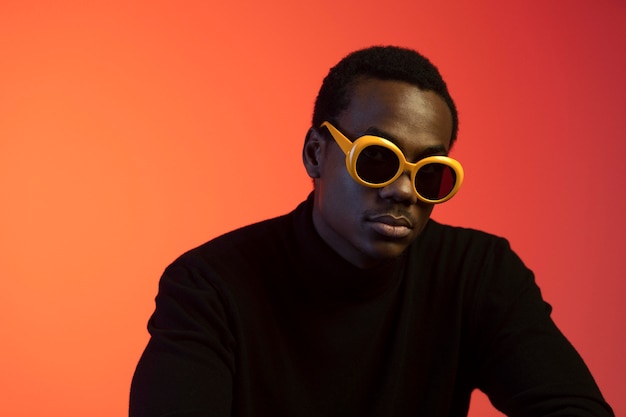 Portrait of handsome man with sunglasses over orange background