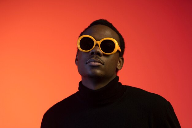 Portrait of handsome man with sunglasses over orange background