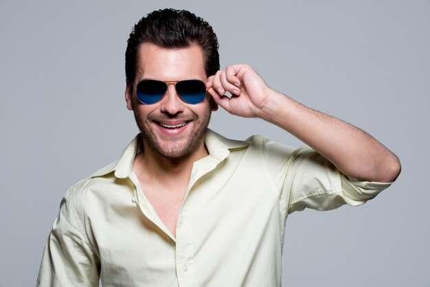 Portrait of handsome man in yellow shirt wearing sunglasses poses 