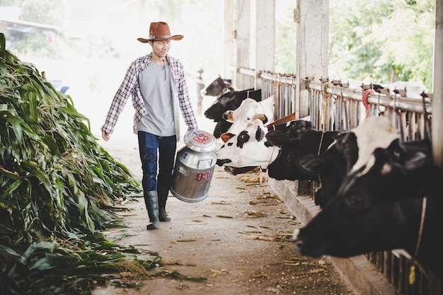 農村部のシーンで屋外ミルクコンテナーと一緒に歩いているハンサムなミルクマンの肖像画