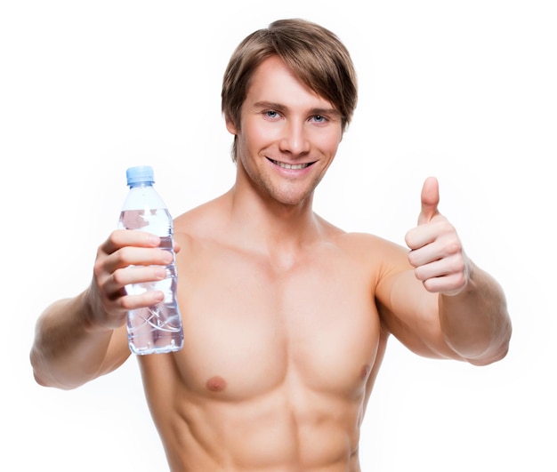 Portrait of handsome muscular shirtless sportsman holds water and show thumbs up sign 