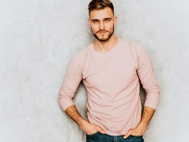 Foto gratuita ritratto del modello serio bello del giovane che indossa i vestiti casuali di rosa di estate. posa alla moda dell'uomo di modo