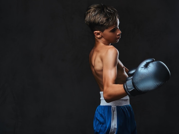 Портрет красивого молодого боксера без рубашки во время боксерских упражнений, сосредоточенного на процессе с серьезным сосредоточенным лицом.