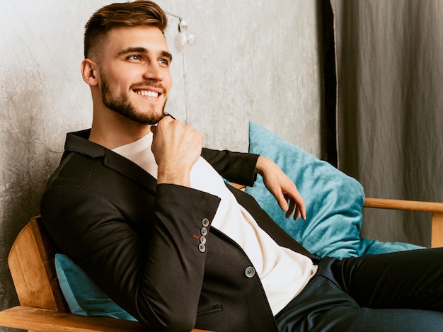 Portrait of handsome smiling hipster  businessman model wearing casual black suit. 