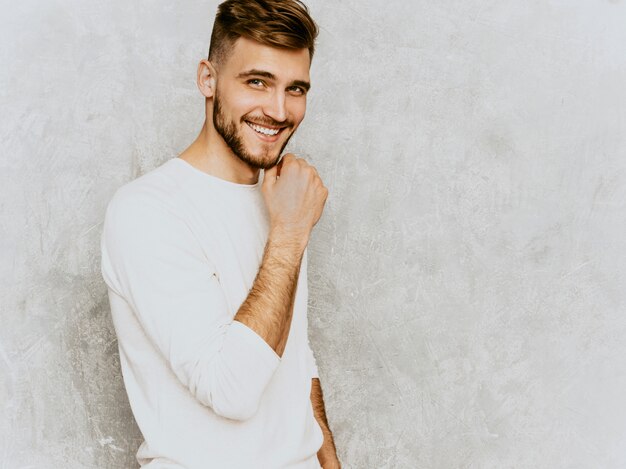 Portrait of handsome smiling hipster   businessman model wearing casual summer white clothes.. Touching his chin