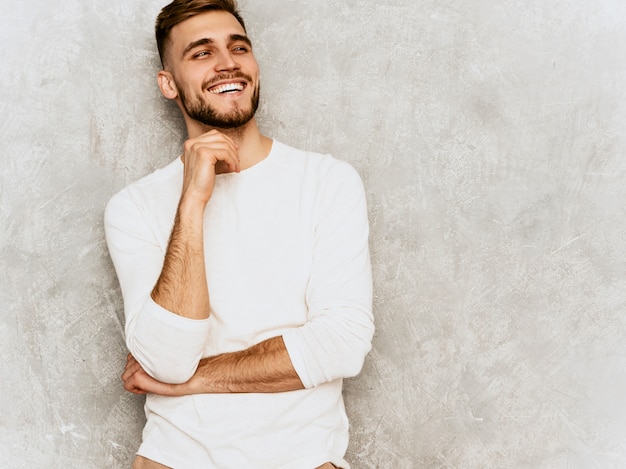 Portrait of handsome smiling hipster   businessman model wearing casual summer white clothes.. Touching his chin
