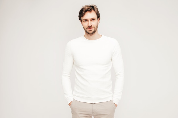 Portrait of handsome smiling hipster lumbersexual businessman model wearing casual white sweater and trousers