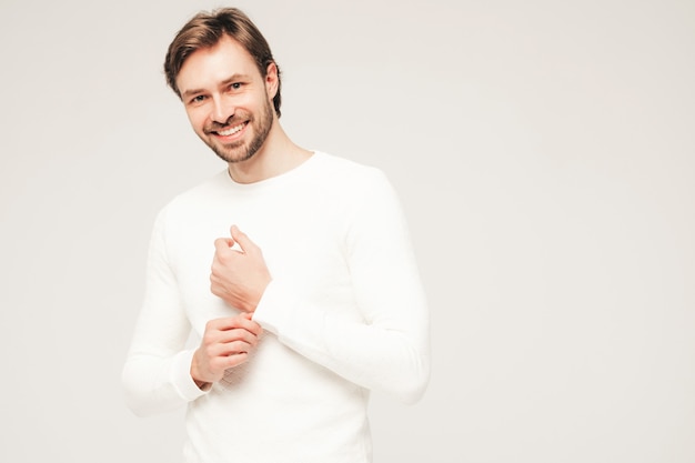 Ritratto di un bell'uomo d'affari lumbersexual hipster sorridente che indossa un maglione e pantaloni bianchi casual