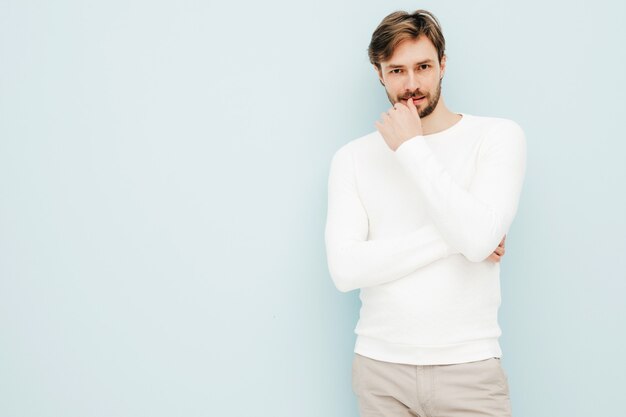 Portrait of handsome smiling hipster lumbersexual businessman model wearing casual white sweater and trousers