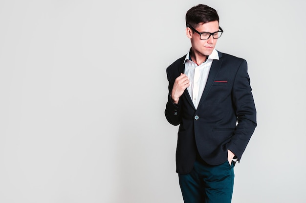 Portrait of handsome smiling model Sexy stylish man dressed in is blue suit Fashion hipster male posing near in white interior in studio