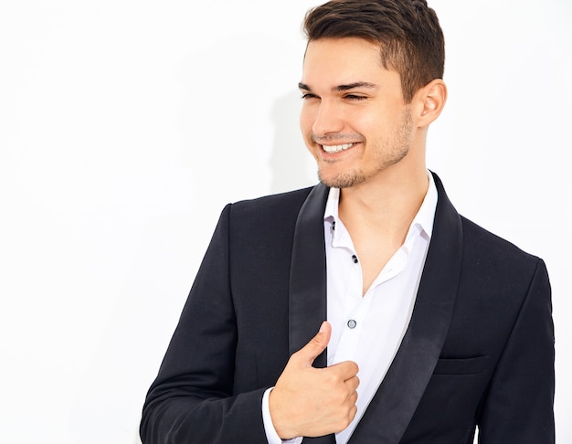 portrait of handsome smiling stylish businessman model dressed in elegant black classic suit posing. Metrosexual