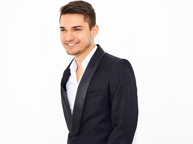 portrait of handsome smiling stylish businessman model dressed in elegant black classic suit posing. Metrosexual