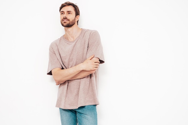 Portrait of handsome smiling stylish hipster lambersexual model Sexy man dressed in pink Tshirt and jeans Fashion male isolated on white wall in studio