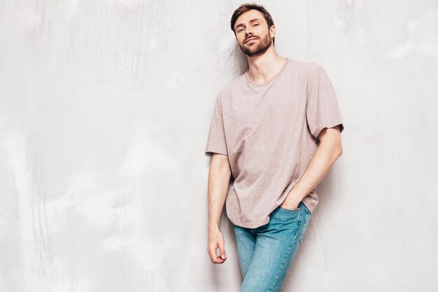 잘 생긴 웃는 세련된 힙스터 램버섹슈얼 모델의 초상화 T셔츠와 청바지를 입은 섹시한 남자 패션 남성 스튜디오에서 파란색 벽에 격리