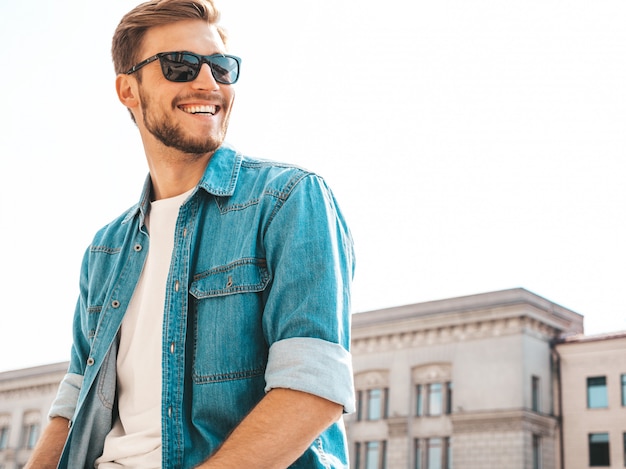 Portrait of handsome smiling stylish hipster lumbersexual businessman model. Man dressed in jeans jacket clothes. 