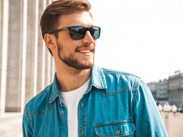 Free photo portrait of handsome smiling stylish hipster lumbersexual businessman model. man dressed in jeans jacket clothes.