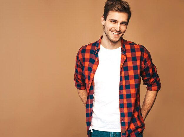 Портрет красивые улыбающиеся стильный молодой человек модель, одетый в красной клетчатой рубашке Модный мужчина позирует